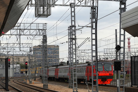 Industrial landscape with arriving passenger train to railroad station on cloudy dayの写真素材