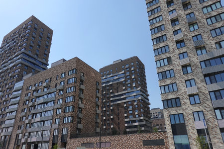 Bottom up view of high modern city buildings with many windows built in the urban cluster