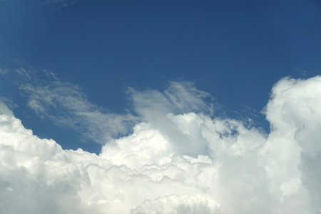 Landscape with blue sky above many white clouds on the bottom of the photo on bright sunny dayの写真素材