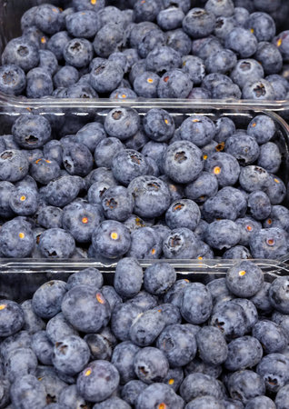 Crop of lot of ripe blueberry in plastic containers as background on store counter close upの写真素材