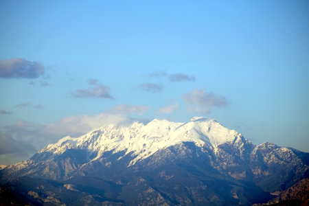 High mountains with large white snow caps on tops under blue sky with some cloudsの写真素材