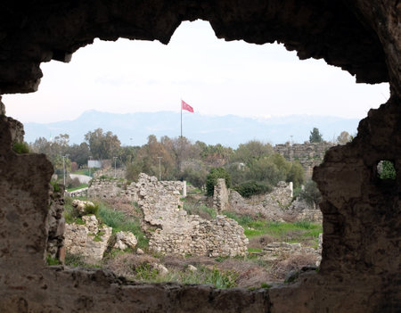 Heritage site Turkish state flag waving on flagpole conceptual view from hole contour in the wall of antique town ruinsの写真素材