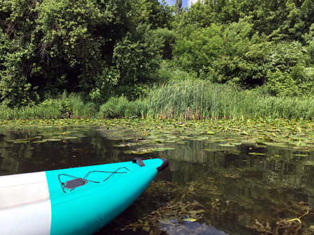 Close up view of fore part of inflatable kayak in the calm backwater river with water lilies in summer dayの写真素材