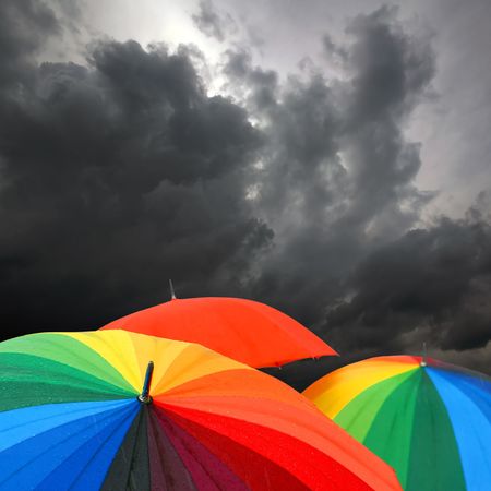 Rainbow collored umbrellas and dark cloudy sky in autumn timeの写真素材