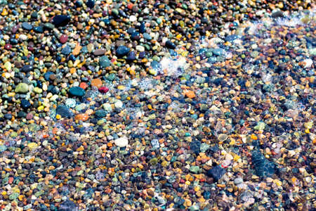 Small colorful wet stones and water on beach in seacoastの写真素材