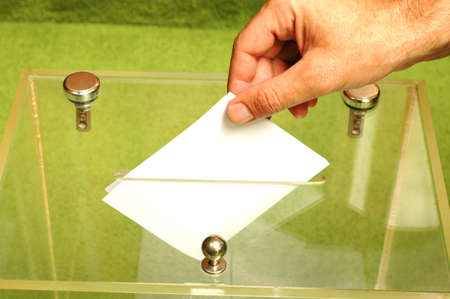 Hand putting a blank ballot inside the box, elections conceptの写真素材