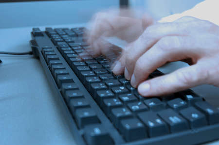 computer room in press office, hand of journalist typing on keyboards, blue toneの写真素材