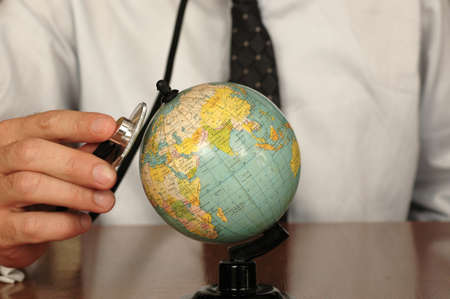 Doctor keeping a stethoscope on a globe, symbol of the desire to heal the Earthの写真素材