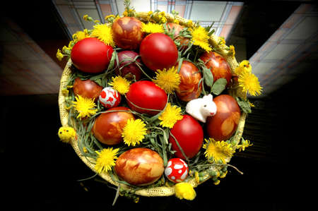 Decorated easter eggs in basket with grass and dandelionの写真素材