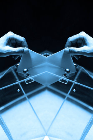 Two hands putting a blank ballot inside the box, voting between different choices, Blue toneの写真素材