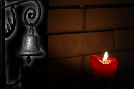 Picture shows old rustic light with a churchbell around the corner with a shadow from a candle light. Background is a brick wall.の写真素材
