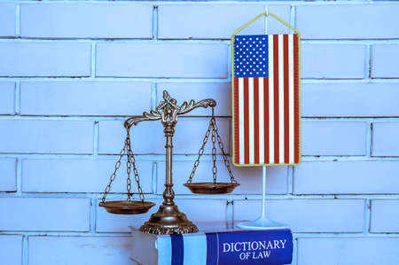 Scales of Justice, american flag, dictionary of law on the brick wall background, BLUE TONE