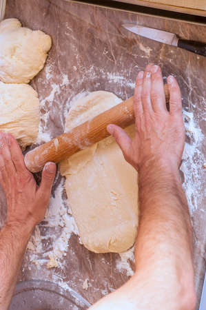 Man working on unfinished dough with a rolling pinの写真素材