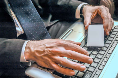 Businessman holding blank business card with laptop on background