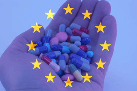 Hand holding multicolored pills, European union flag backgroundの写真素材