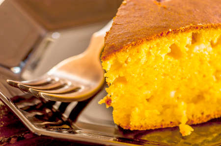macro shot of cornbread with a fork on a black plate. selective focus
