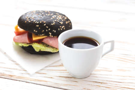 Black Hamburger with ham, cheese, cucumber, tomato and lettuce, cup of coffee for breakfast....
