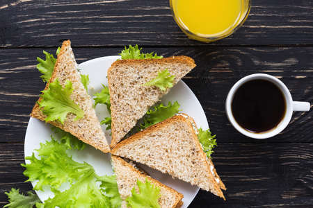 Toasts with cottage cheese and lettuce, cup of coffee and orange juice for breakfast. Selective focusの写真素材