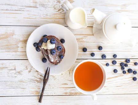 Hot tea and buckwheat chocolate pancakes with blueberries and sour cream. Closeup. Breakfast and Love Conceptの写真素材