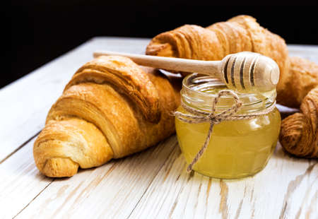 Fresh Croissants and honey. Wooden table. Selective focusの写真素材