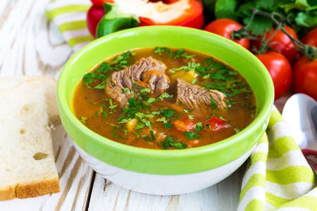 Caucasian lamb or beef Shurpa soup with vegetables at wooden table. Closeup.の写真素材