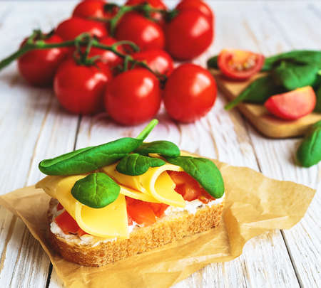 Bruschetta with spinach, cheese and cherry tomatoes on slices of toasted baguette or ciabatta. Traditional Italian appetizers. European cuisine.の写真素材