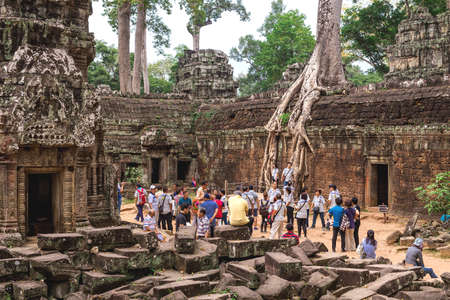 Ta Prohm, Siem Reap, Cambodia - December 7, 2016: Huge trees, galleries and walking tourists at...
