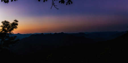 View of mountain peaks, coniferous tropical forest and green meadow in summer landscape. Sunset in Thailand. Panoramaの写真素材