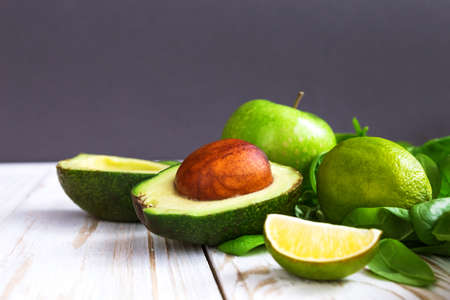 Wooden background with healthy green spinach, lime, avocado and apple. Healthy food concept