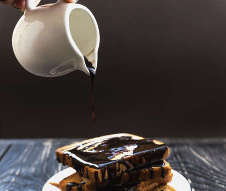 Fresh Toast with hot chocolate spread on white plate. Wooden table. Selective focusの写真素材