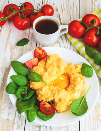 Baked Eggs Orsini with spinach and cherry tomatoes and cup of coffee. Traditional French breakfast. European cuisineの写真素材