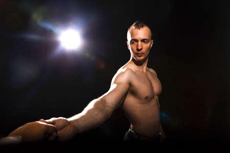 Healthy young man with strong arms and muscular male torso. Black background.  Fitness conceptの写真素材