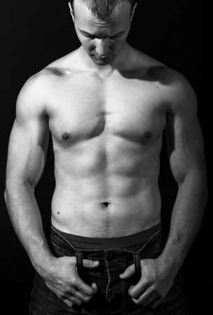 Healthy young man with strong arms and muscular male torso. Black background.  Fitness conceptの写真素材