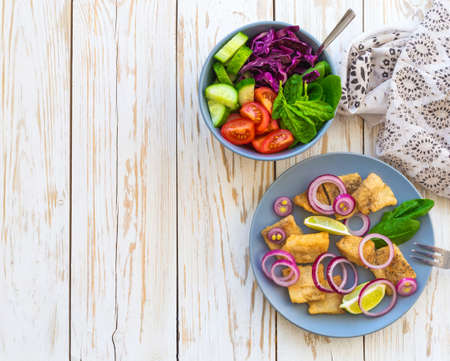 Crispy fried fish tilapia with lime and onion; and green vegetable salad. Selective focus. Closeupの写真素材