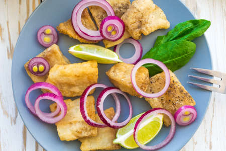 Crispy fried fish tilapia with lime and pickled onion. Selective focus. Closeup.の写真素材