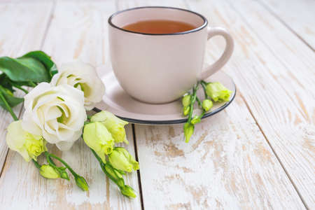 Cup of hot tea and white eustoma flowers. Spring conceptの写真素材