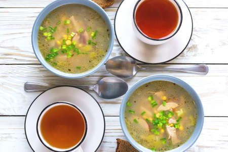 Traditional Nigerian corn and smoked chicken clear soup and tea for breakfast at wooden table. Closeup.の写真素材