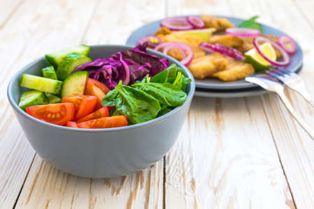 Crispy fried fish tilapia with lime and onion; and green vegetable salad. Selective focus. Closeupの写真素材