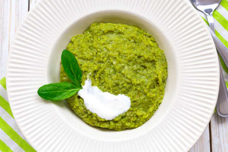 Green pease puree pudding with spinach and spices at wooden table. Closeup. Vegetarian and healthy food conceptの写真素材