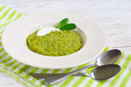 Green pease puree pudding with spinach and spices at wooden table. Closeup. Vegetarian and healthy food conceptの写真素材