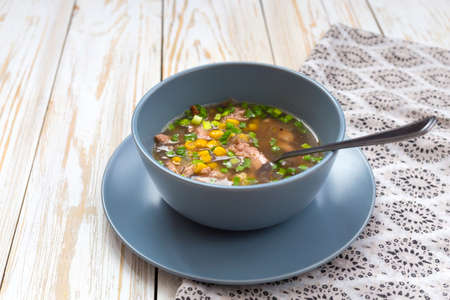 Traditional Nigerian corn and smoked chicken clear soup at wooden table. Closeup.の写真素材
