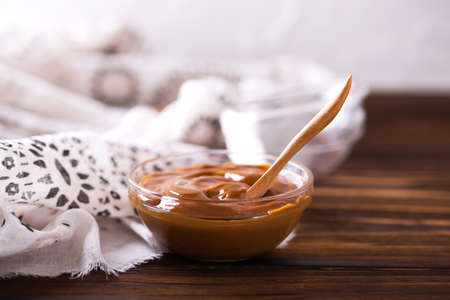 Bowl of homemade melted caramel sauce on wooden backgroungの写真素材