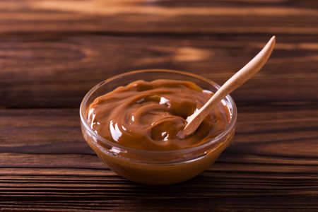 Bowl of homemade melted caramel sauce on wooden backgroungの写真素材