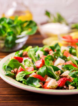Fresh salad with strawberry, spinach leaves, corn salad, walnuts and goat cheese. Healthy food conceptの写真素材