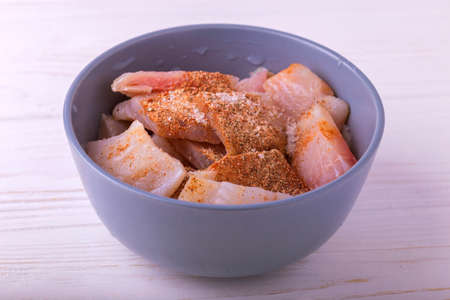 Ingridients for cooking crispy fried fish tilapia. Chopped raw fillet in clay bowl with spices. Healthy food conceptの写真素材