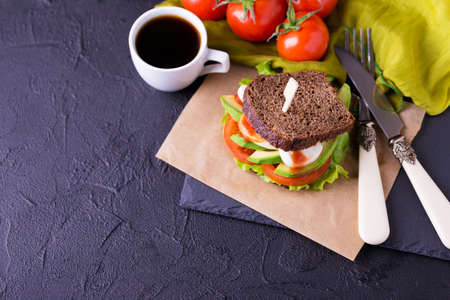 Rye bread sandwich with cherry tomatoes, lettuce green salad, avocado, boiled egg and tomato sauce and espresso coffee for breakfast. Selective focusの写真素材
