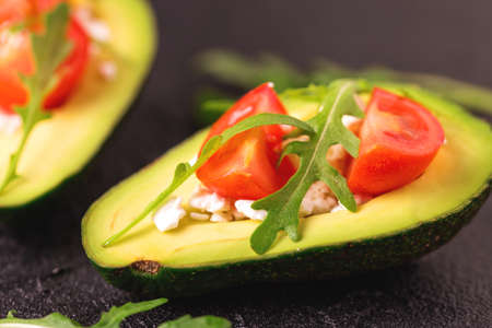 Avocado boats stuffed with feta cheese, arugula and cherry tomatoes. Salad. Healthy food and dieting concept.の写真素材