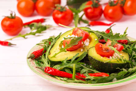 Avocado boats stuffed with feta cheese, arugula and cherry tomatoes. Salad. Healthy food and dieting concept.の写真素材