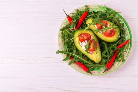 Avocado boats stuffed with feta cheese, arugula and cherry tomatoes. Salad. Healthy food and dieting...