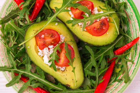 Avocado boats stuffed with feta cheese, arugula and cherry tomatoes. Salad. Healthy food and dieting...